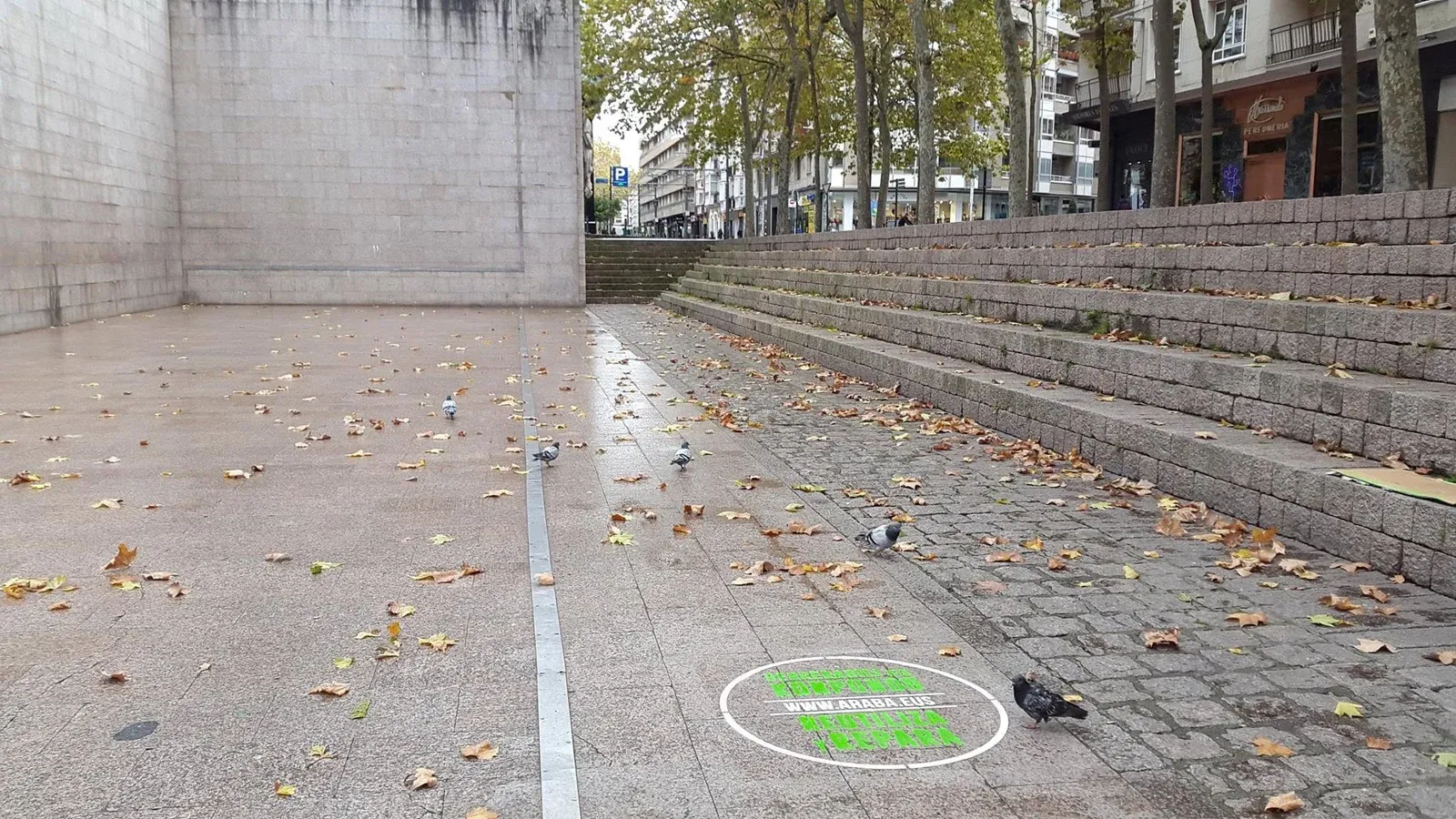 Graffiti de Tiza verde integrado en una plaza urbana con tránsito peatonal.